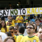 epa04274733 Brazil supporters hold a banner reading 'Say No to Racism' prior the FIFA World Cup 2014 group B preliminary round match between Australia and Spain at the Arena da Baixada in Curitiba, Brazil, 23 June 2014. (RESTRICTIONS APPLY: Editorial Use Only, not used in association with any commercial entity - Images must not be used in any form of alert service or push service of any kind including via mobile alert services, downloads to mobile devices or MMS messaging - Images must appear as still images and must not emulate match action video footage - No alteration is made to, and no text or image is superimposed over, any published image which: (a) intentionally obscures or removes a sponsor identification image; or (b) adds or overlays the commercial identification of any third party which is not officially associated with the FIFA World Cup) EPA/JUANJO MARTIN EDITORIAL USE ONLY