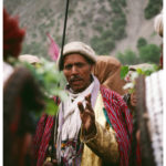 Un homme de savoir vêtu de vêtements de cérémonie profère une louange à un donneur de fête